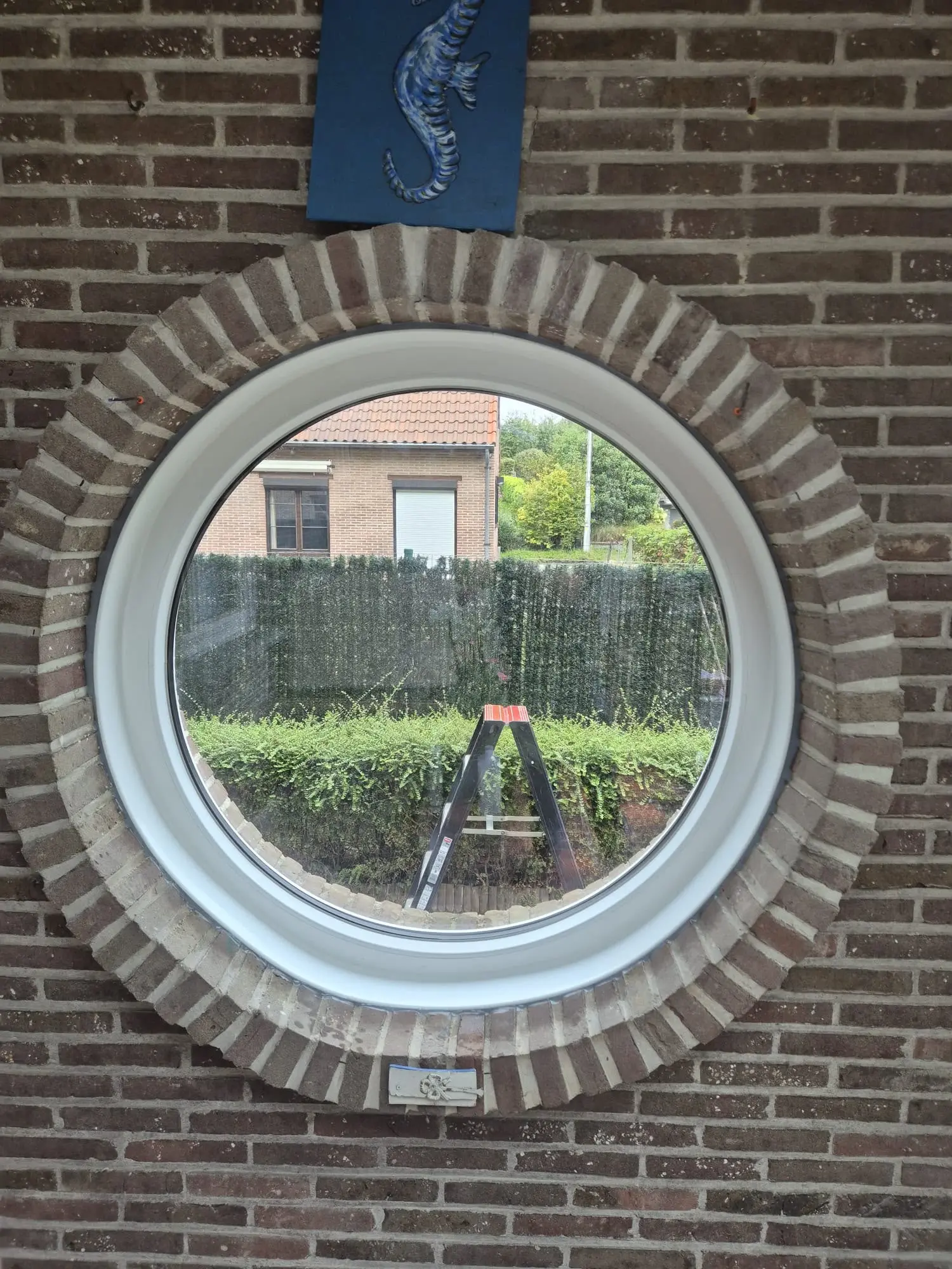 Fenêtre ronde blanche intégrée dans une façade en briques